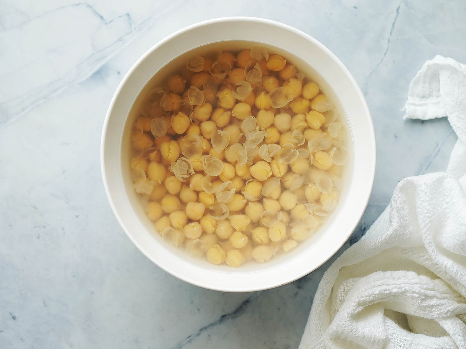 A bowl with cooked chickpeas in water.