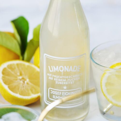 A jar of lemonade with fresh lemons on the side.