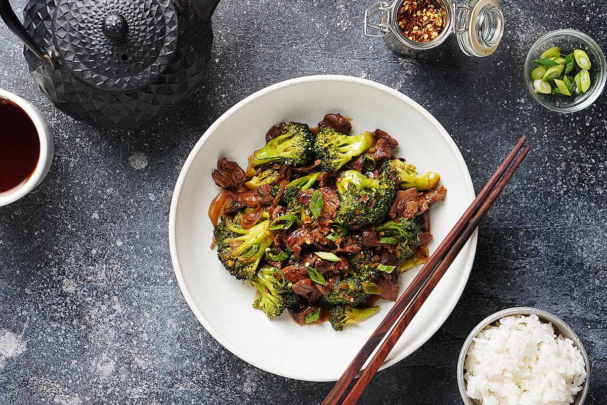Cooked beef & broccoli stir fry in a bowl on a dark table background.