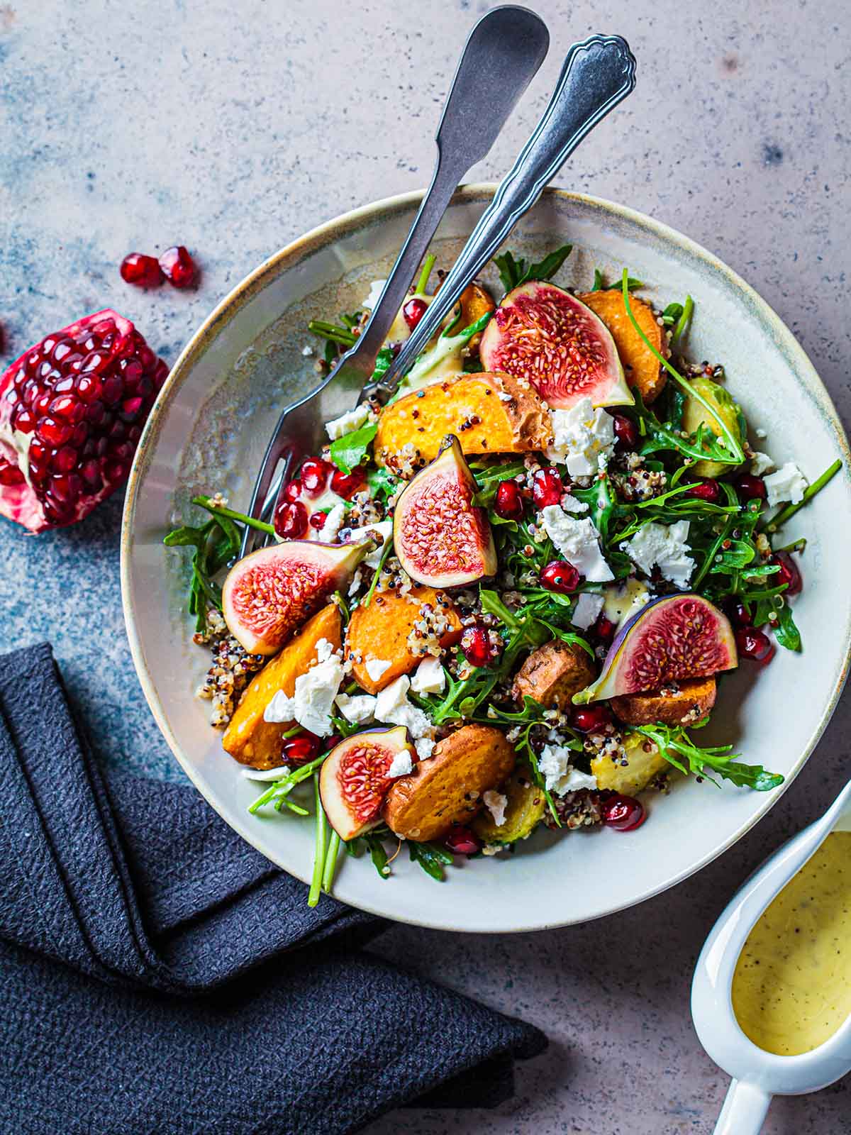 Warm autumn quinoa salad with baked vegetables (sweet potato, Brussels sprouts), figs, feta cheese and pomegranate, top view.