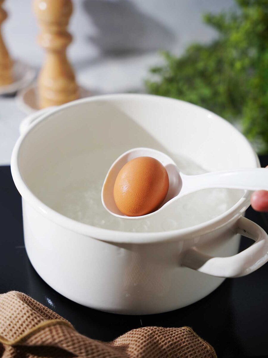 Grabbing an egg with a plastic spoon from the boiling water.