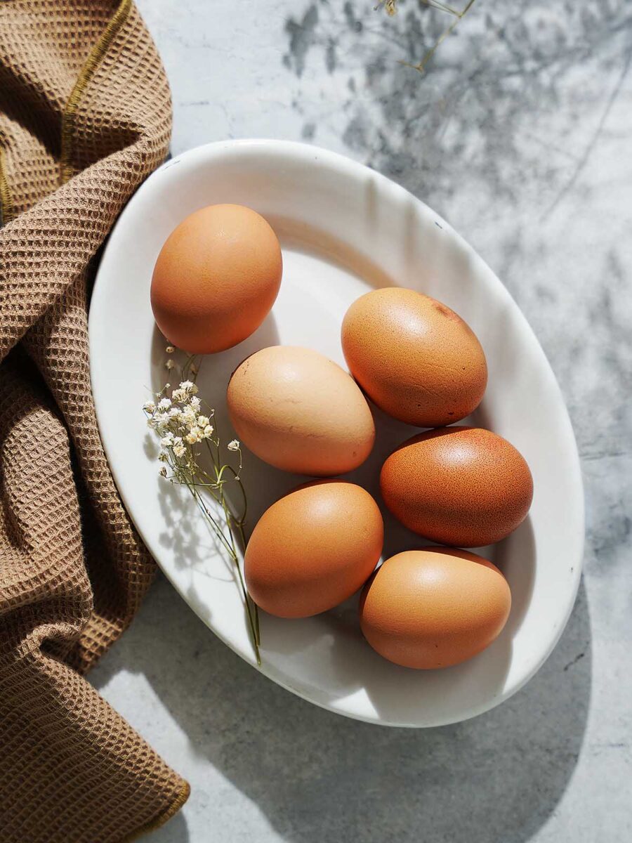 Six brown eggs on a white oval plate.