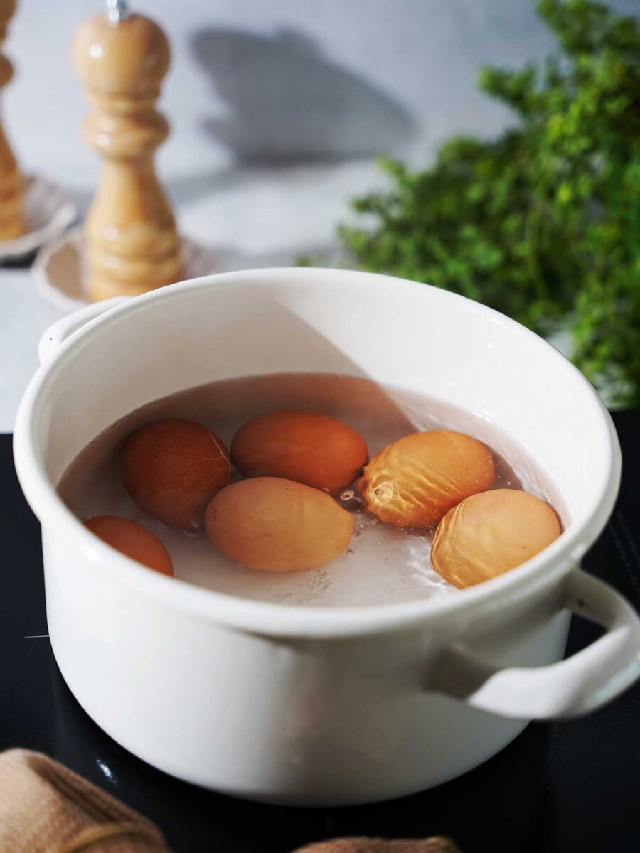 Boiling eggs in a white pot.