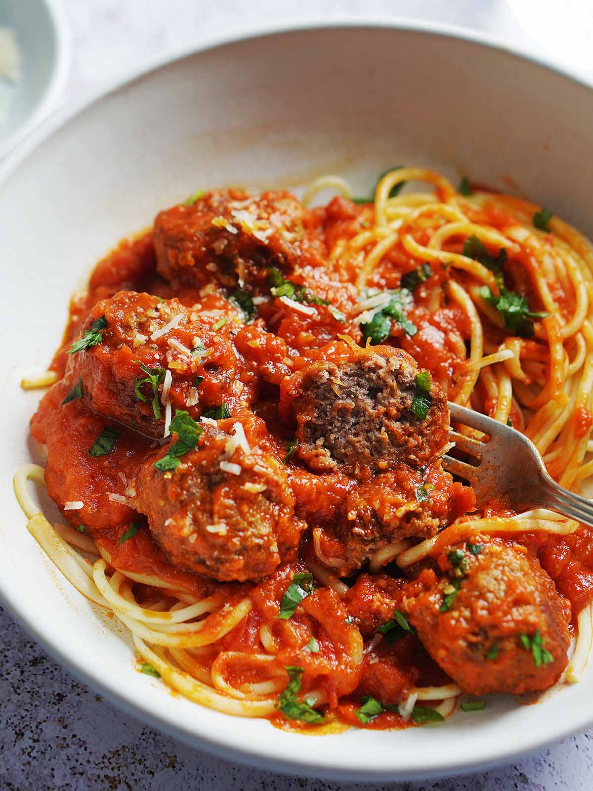 An bowl with meatballs over spaghetti and sauce.