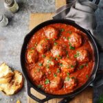 Beef meatballs in a skillet with marinara sauce.